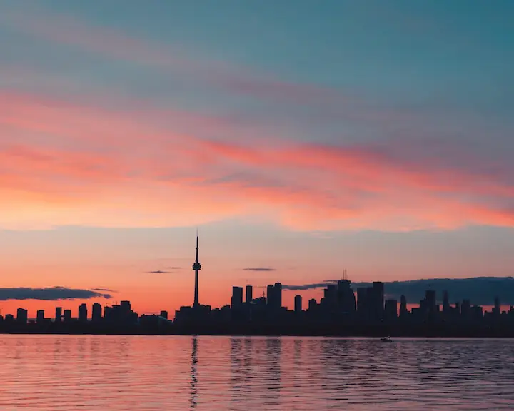 pink and blue sky sunset with some clouds and Toronto skyline silhouette in the background taken by Brice Lan