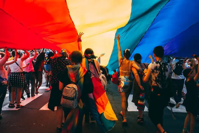 people enjoying pride sheltered under a pride flag