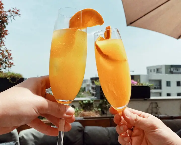 Two people cheers mimosas