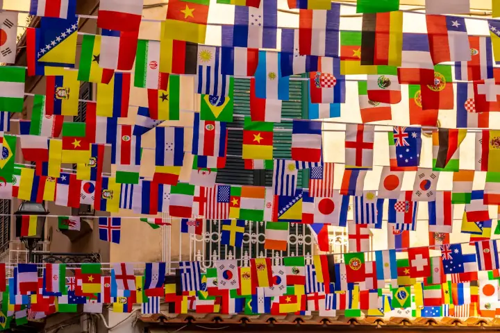 flags of different countries hung overhead with a balcony in the background