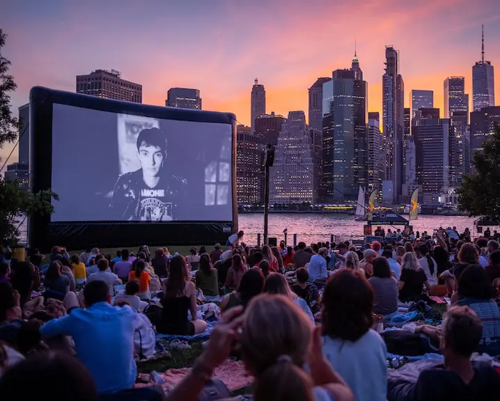 Outdoor movie in a city by a body of water at sunset