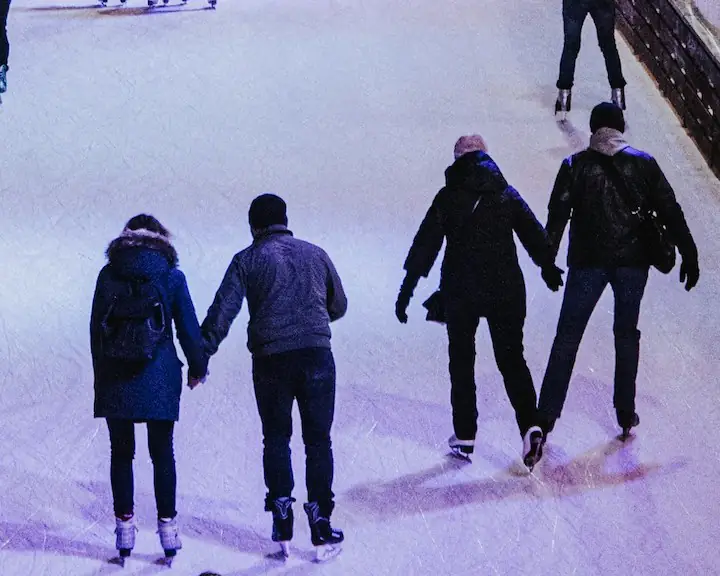 Couples holding hands while skating on skating rink
