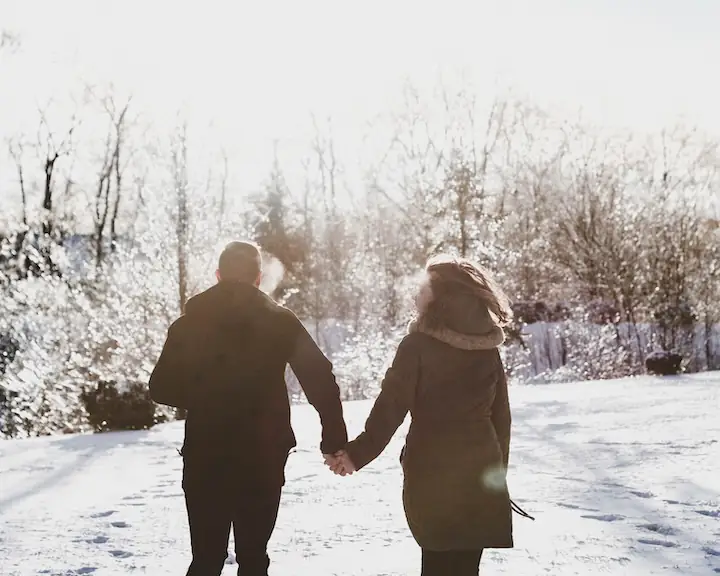 couple holding hands with backs towards the camera in a winter nature scene by @lianhao_qu